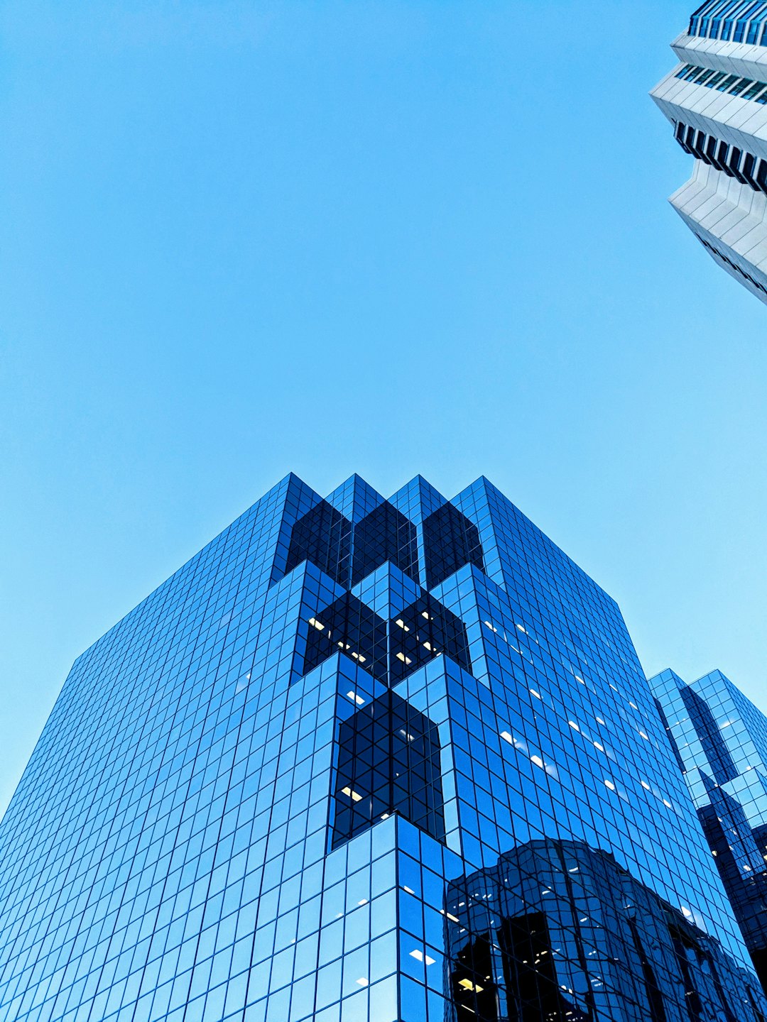 Modern skyscraper with blue glass facade against a clear sky.