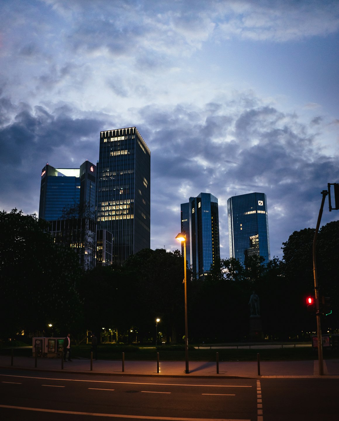 Modern skyscrapers rise above a city street at twilight.