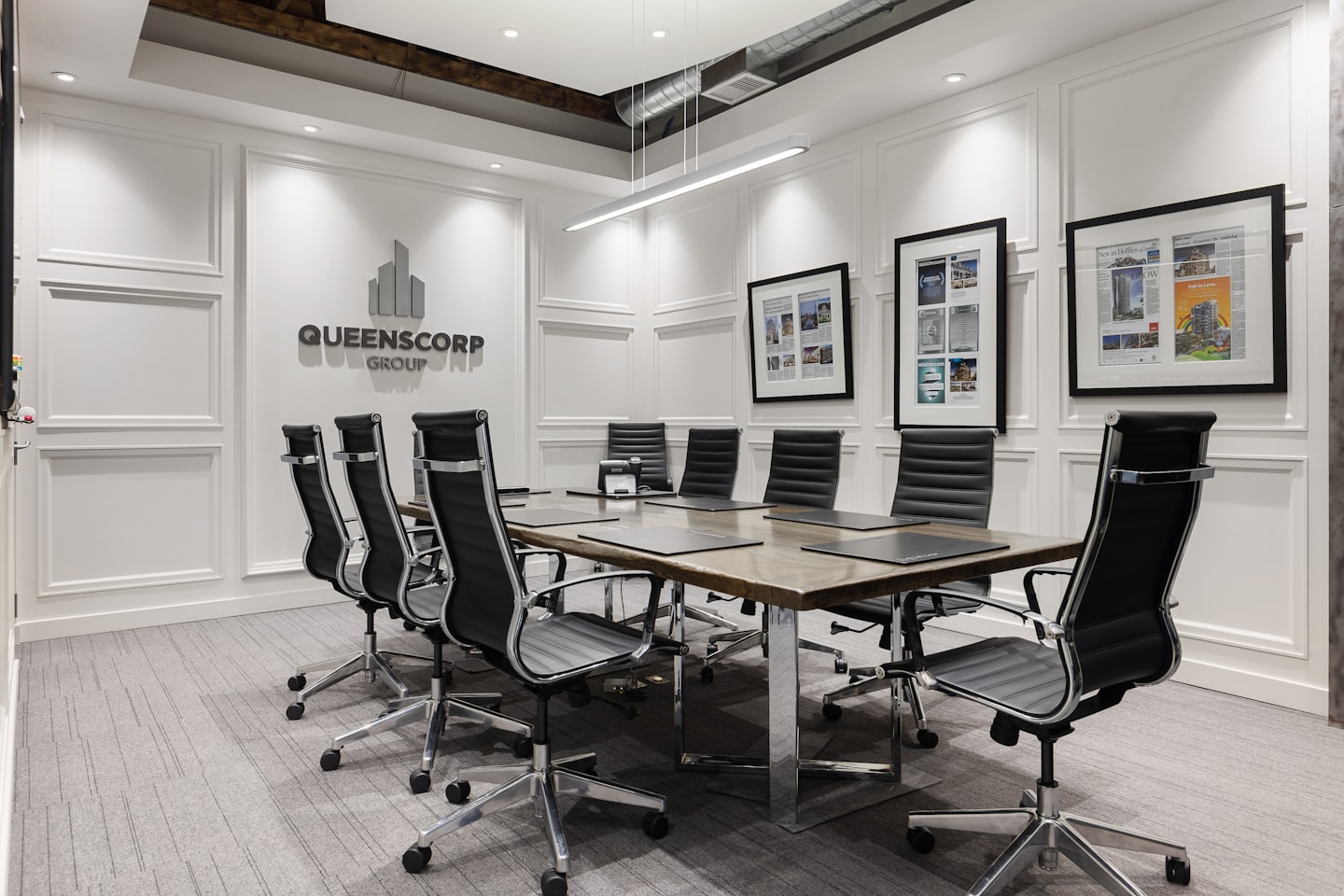 Conference room with long table and Queenscorp Group logo.
